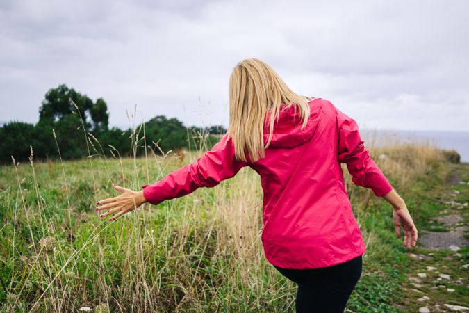 Cheerful woman enjoying countryside landscape stretching hands
