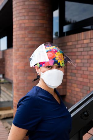 Portrait of female nurse in face shield, N95 mask and scrubs outside