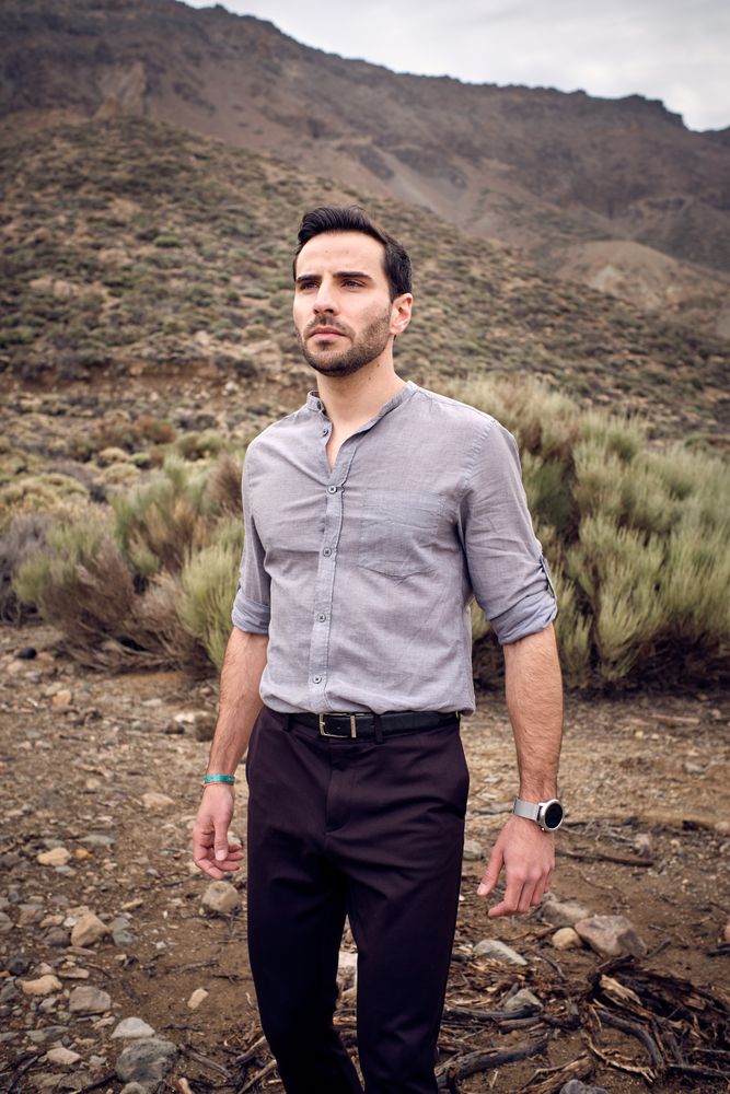 Confident young man standing on stony terrain with savanna grass