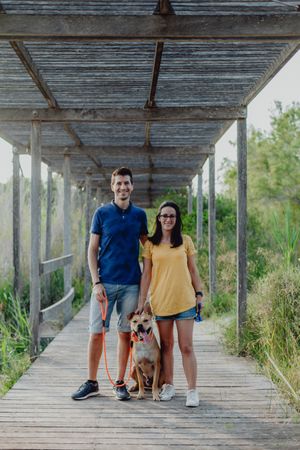 Happy adult couple standing with dog at countryside