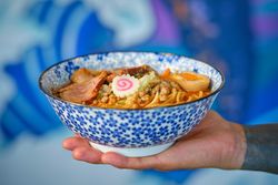 Anonymous person holding bowl of yummy Asian noodle soup