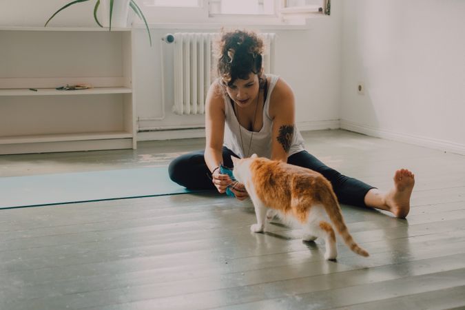 Relaxed woman playing with cat on floor at home