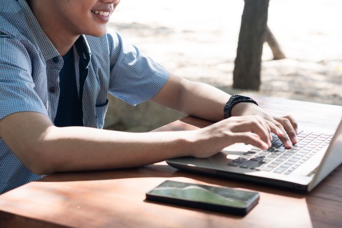 Close up Happy Asian Young businessman work at outdoor with laptop. Concept of remote and freelance work. Young successful man wearing casual blue cloth.