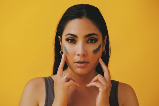 Latina woman with her hands to her face applying mud mask, copy space