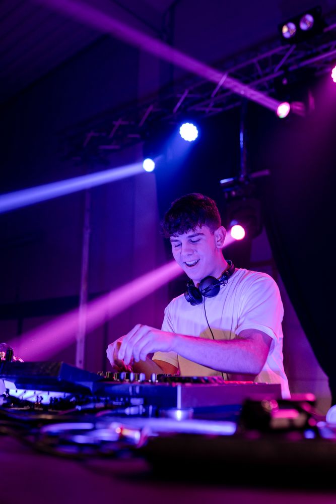 Happy Young DJ mixing in a disco with neon lights