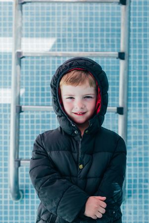 Boy in warm clothes standing in empty pool