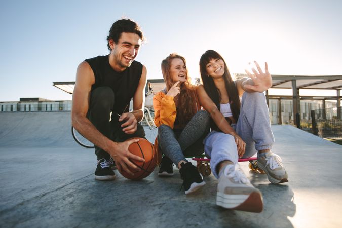 Young man and women sitting at skate park and smiling