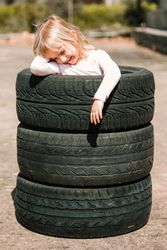 Little girl resting in stack of tires