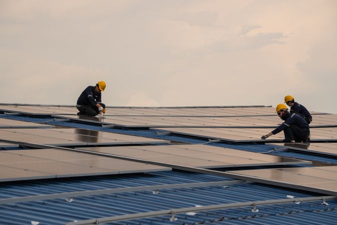 Engineer team checking solar cell  or photovoltaic cell by computer laptop installed on the roof of the factory. Technician worker repair or inspect the system. Industrial renewable energy concept