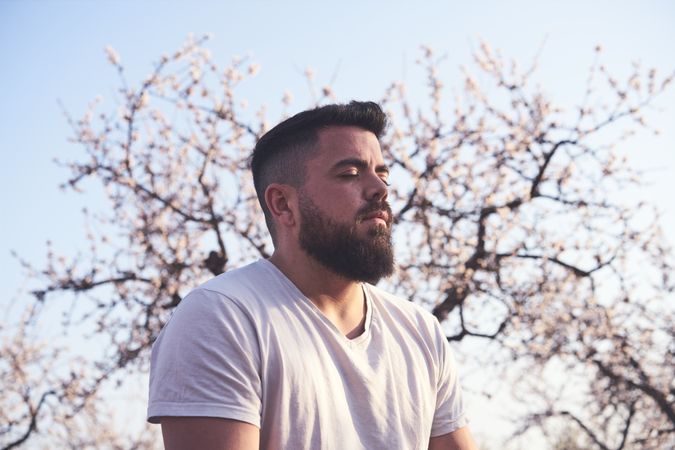 Bearded man meditating in spring garden