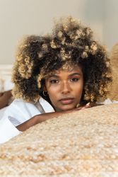 Thoughtful Black woman lying on bed in bedroom