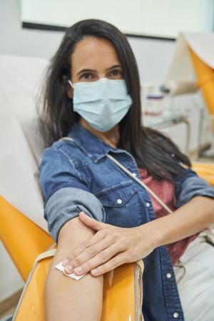 Woman in mask putting white cotton on arm