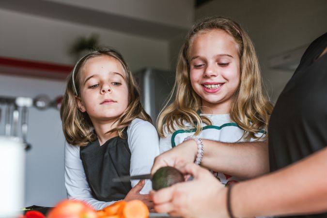 Anonymous adult preparing vegetables for salad with kids