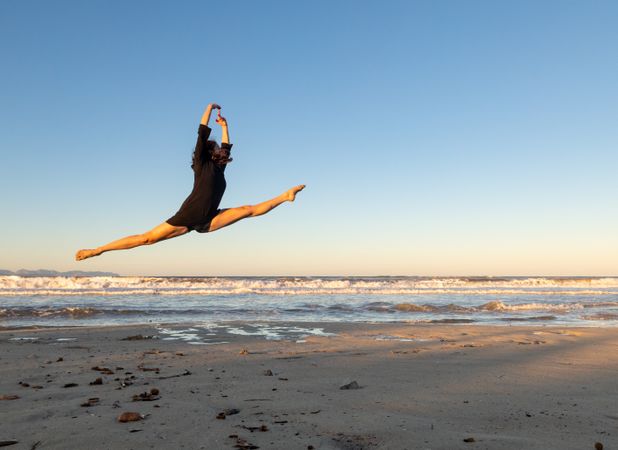 Woman jumping near water on shore
