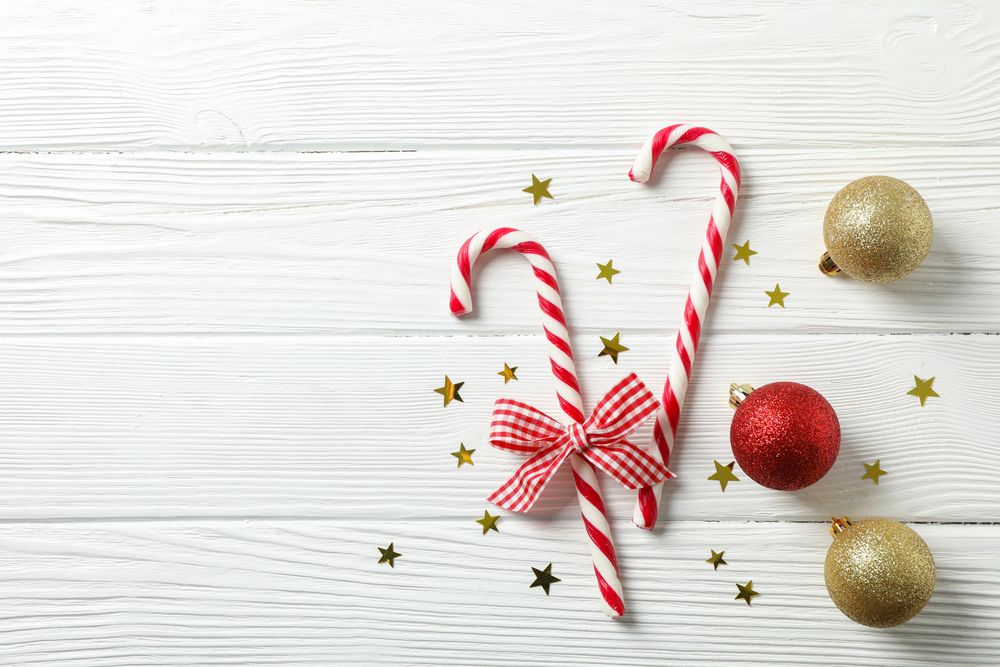 Candy canes and christmas accessories on wooden background, space for text