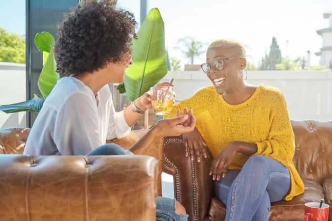 Cheerful friends communicating on couch at home