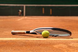 Tennis racket and ball on a dirt court