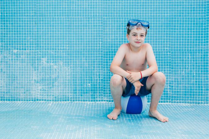 Boy sitting on ball in empty pool