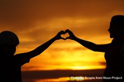 Silhouette of two people making heart shape with their hands during sunset 5zpaNb