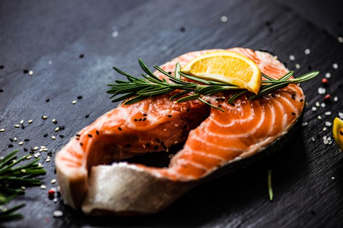 Salmon fish with rosemary and lemon on dark counter with copy space