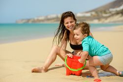 Mother and son playing with toys on sandy beach
