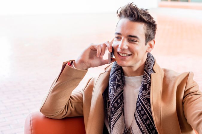 Smiling man sitting outside talking on cellphone