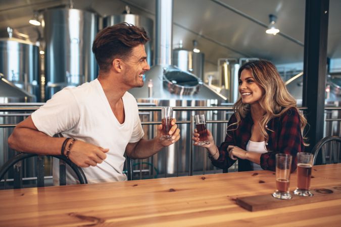 Young couple toasting with beer sample glasses at brewery