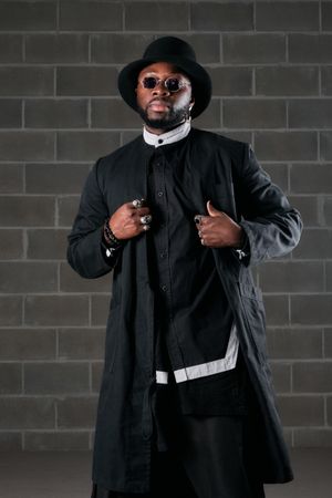 Serious trendy man in black outfit and top hat
