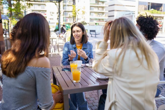Woman explaining something to her friends at an outside table