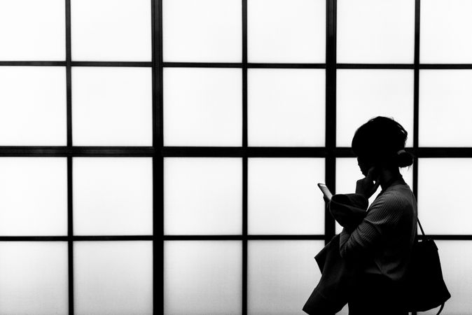 Silhouette of a woman holding smartphone in grayscale