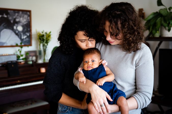 Two woman tendering holding their newborn baby at home