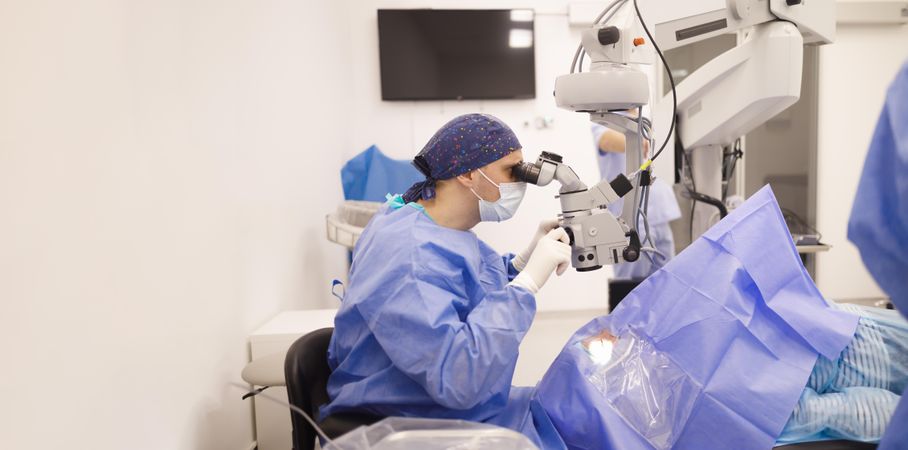 Doctor looking through eye equipment at patient in cataract surgery