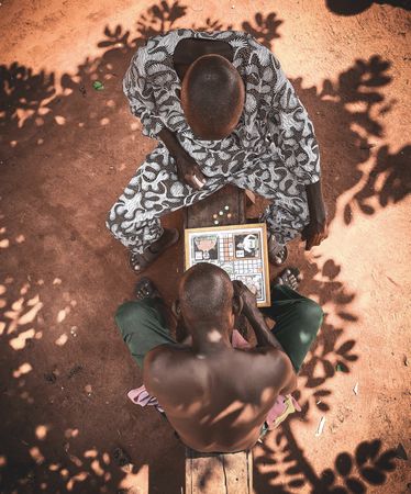 Top view of two African men playing boardgame outdoor