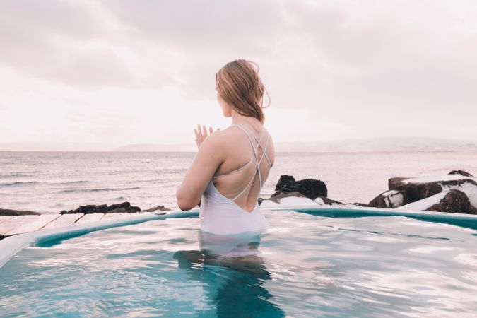 Woman sitting in pool near stones