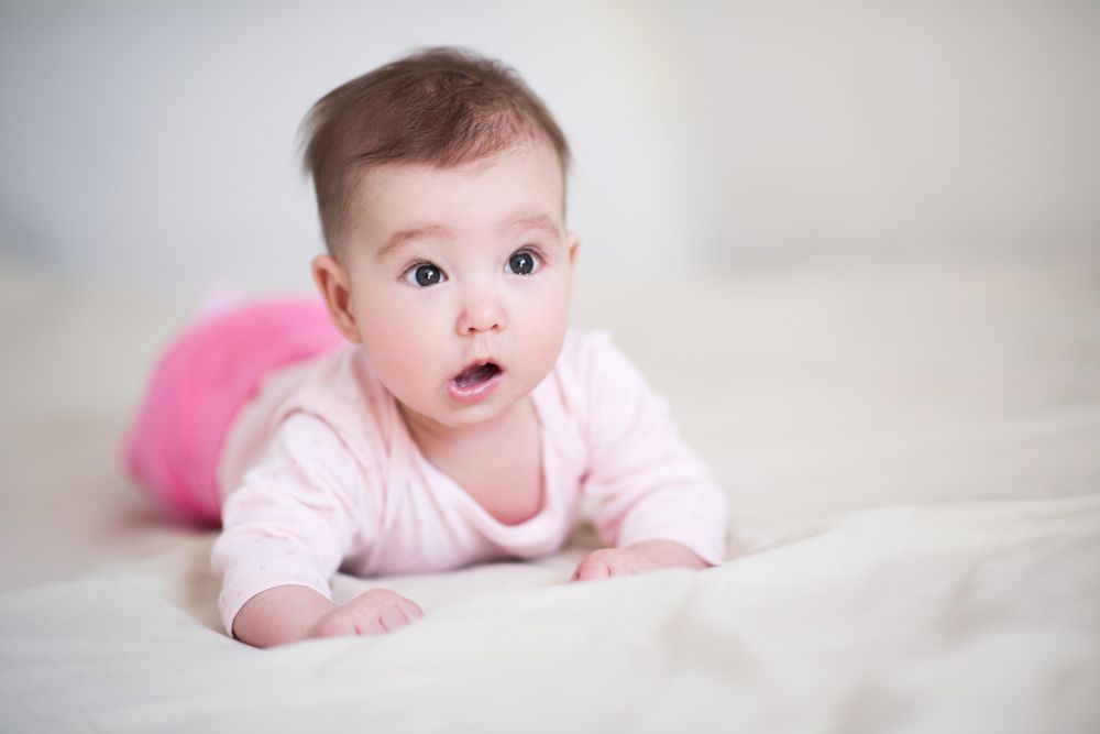 Studio shot of baby in pink pant and shirt crawling