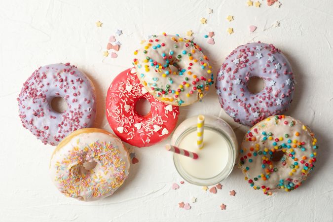 Milk and tasty donuts on plain background, top view