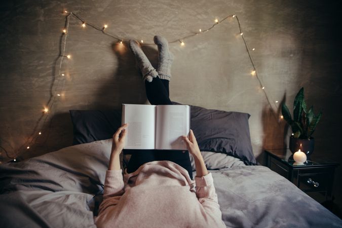 Woman lying on bed and reading book