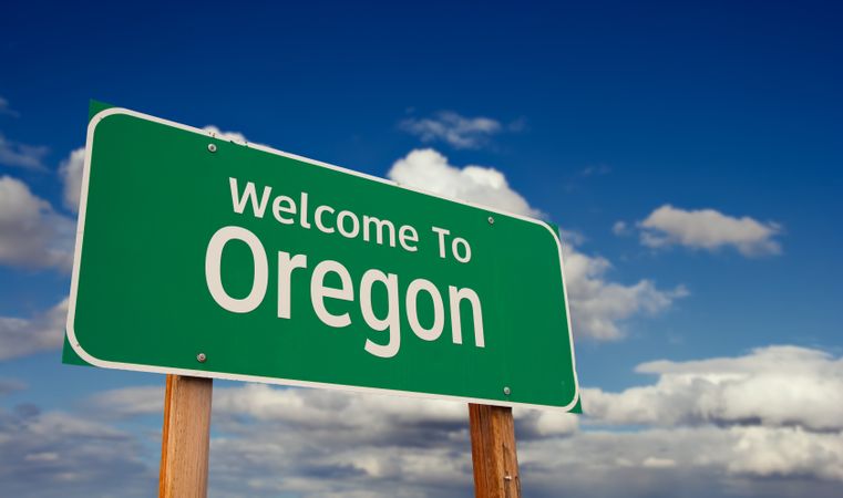 Welcome To Oregon Green Road Sign Over Blue Sky with Some Clouds.