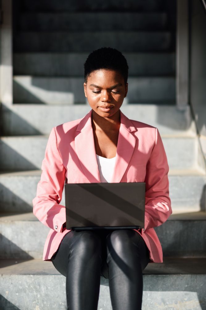 Female in pink suit working on shadowy stairs outside