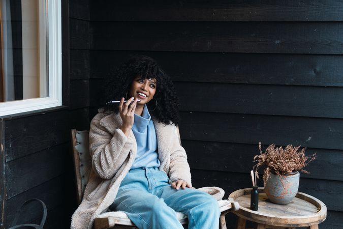 Cheerful Black woman recording voice message on terrace