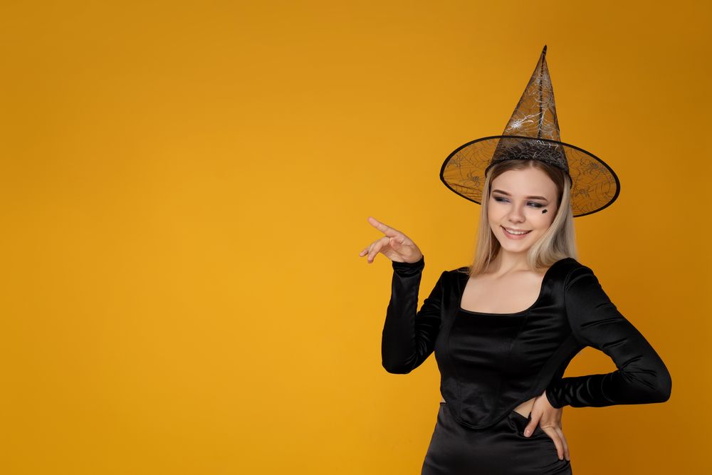 Concept of Halloween, young woman on yellow background