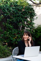 Transgender woman working in a garden with laptop and smartphone
