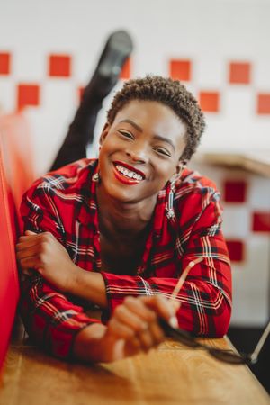 Gorgeous stylish Black woman lying on seats in cafe