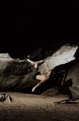 Man practicing rock climbing among large rocks in a forest