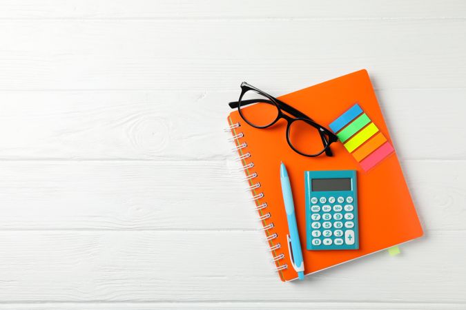 Orange notebook with glasses and stationary on table with copy space