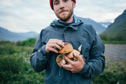 Man in windbreaker holding mushrooms