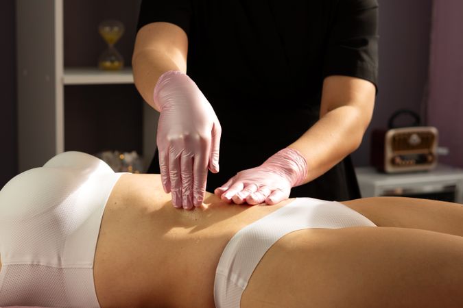 Spa therapist performs abdominal massage with circular hand movements.