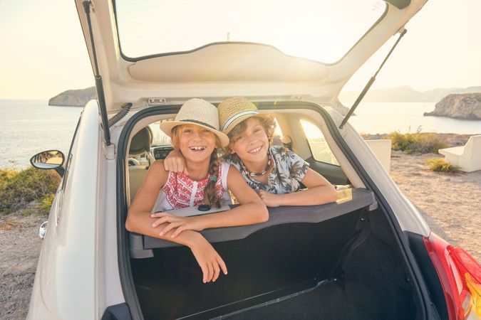 Brother embracing his sister while is smiling and wearing straw