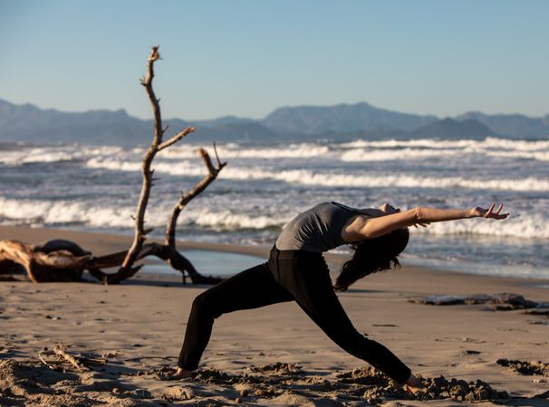 Young woman dancing and posing near water on shore