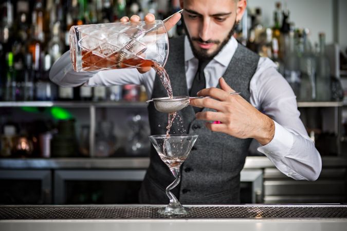 Bartender straining a cocktailing into a glass
